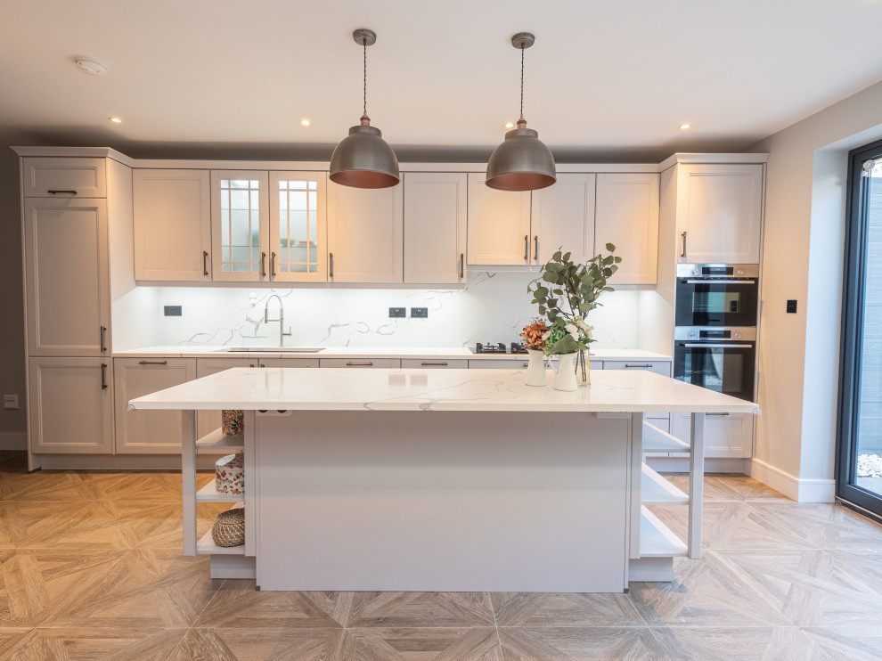 This is an example of a large victorian single-wall kitchen/diner in London with a double-bowl sink, shaker cabinets, quartz worktops, white splashback, engineered quartz splashback, stainless steel appliances, ceramic flooring, an island, brown floors and white worktops.