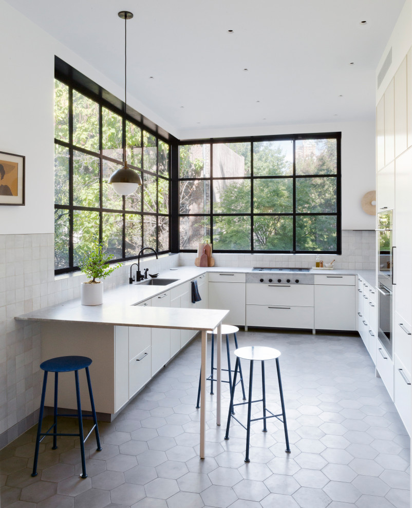 Inspiration for a large contemporary u-shaped eat-in kitchen in New York with an undermount sink, flat-panel cabinets, marble benchtops, grey splashback, ceramic splashback, stainless steel appliances, cement tiles, a peninsula, grey floor, grey benchtop and white cabinets.