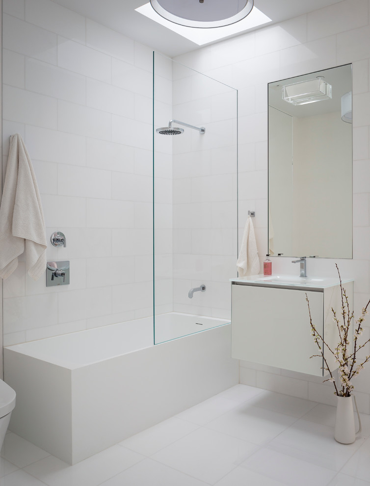 Photo of a modern bathroom in San Francisco with flat-panel cabinets, white cabinets, a shower/bathtub combo and white tile.