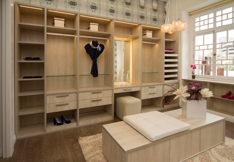 Mid-sized contemporary gender-neutral walk-in wardrobe in Houston with flat-panel cabinets, light wood cabinets and ceramic floors.
