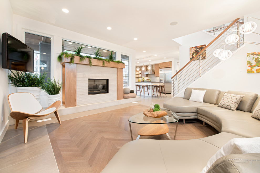 Contemporary living room in Calgary with a brick fireplace surround, a wall-mounted tv, white walls, medium hardwood floors and a standard fireplace.