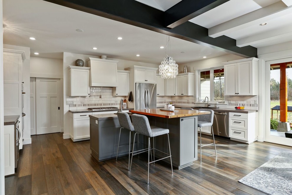 Transitional l-shaped kitchen in Seattle with shaker cabinets, white cabinets, stainless steel appliances, dark hardwood floors, with island and brown floor.