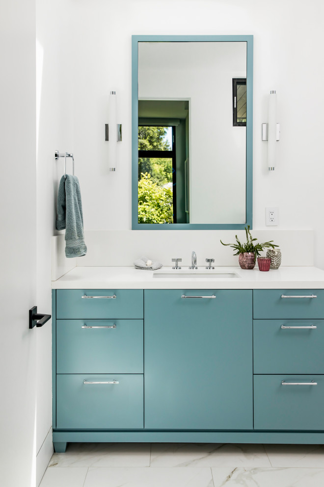 Photo of a large contemporary kids bathroom in San Francisco with blue cabinets, white walls, an undermount sink, white benchtops, an enclosed toilet, a single vanity, a built-in vanity, wallpaper, flat-panel cabinets, an alcove tub, a shower/bathtub combo, a one-piece toilet, white tile, glass tile, porcelain floors, engineered quartz benchtops and a hinged shower door.