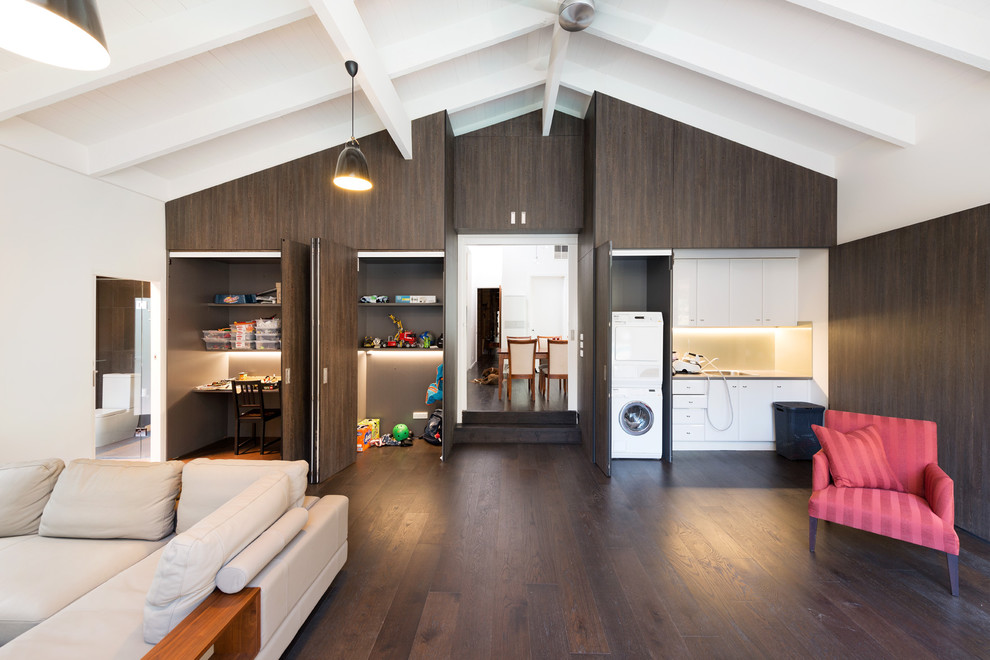 This is an example of a contemporary open concept family room in Melbourne with white walls and dark hardwood floors.