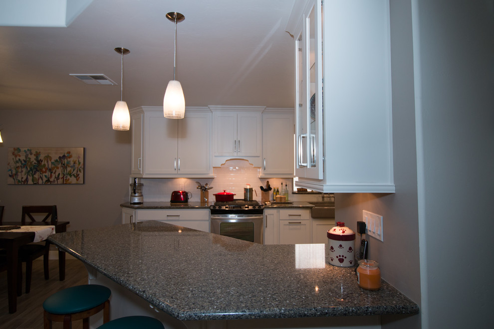 Mid-sized transitional galley porcelain tile open concept kitchen photo with a farmhouse sink, shaker cabinets, white cabinets, quartz countertops, white backsplash, subway tile backsplash and stainless steel appliances
