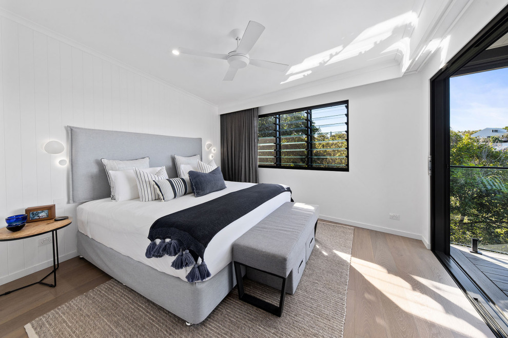 This is an example of a small coastal master bedroom in Sunshine Coast with white walls, light hardwood flooring, beige floors, a vaulted ceiling and wainscoting.