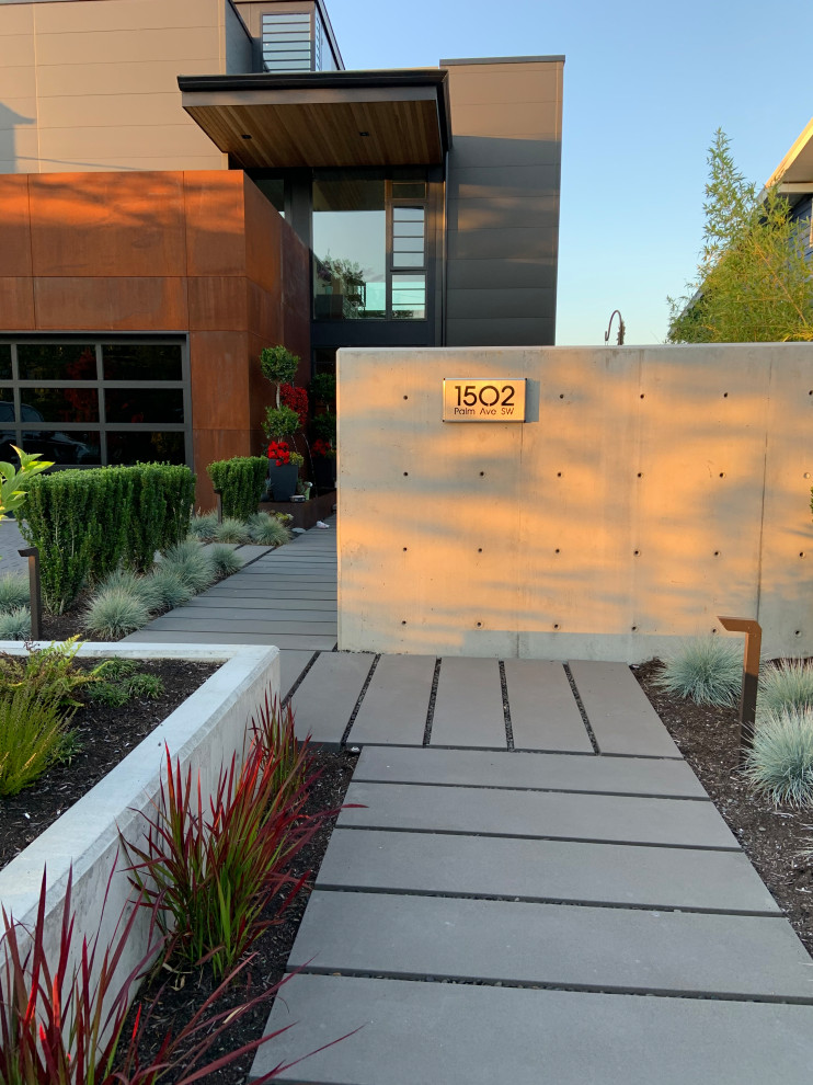 This is an example of a mid-sized contemporary front yard full sun xeriscape in Seattle with concrete pavers and a metal fence.