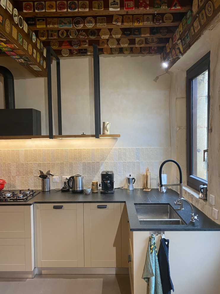 Foto di una cucina lineare country di medie dimensioni con lavello a doppia vasca, paraspruzzi beige, paraspruzzi con piastrelle in ceramica, nessuna isola e top nero