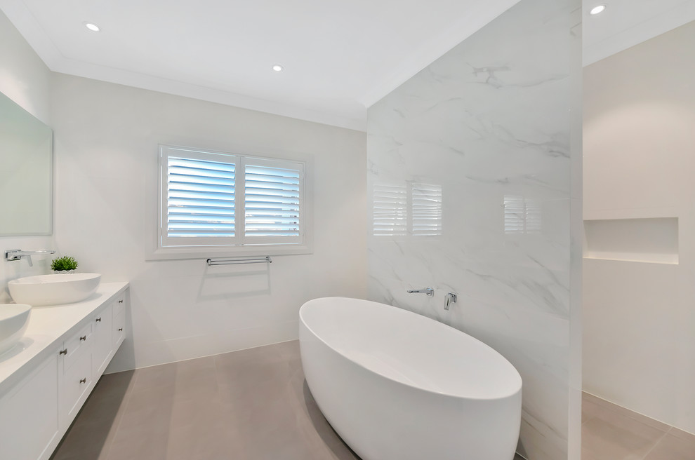 Design ideas for a large contemporary kids bathroom in Sydney with recessed-panel cabinets, white cabinets, a freestanding tub, an open shower, a one-piece toilet, white tile, marble, white walls, porcelain floors, a trough sink, engineered quartz benchtops, brown floor, an open shower and white benchtops.