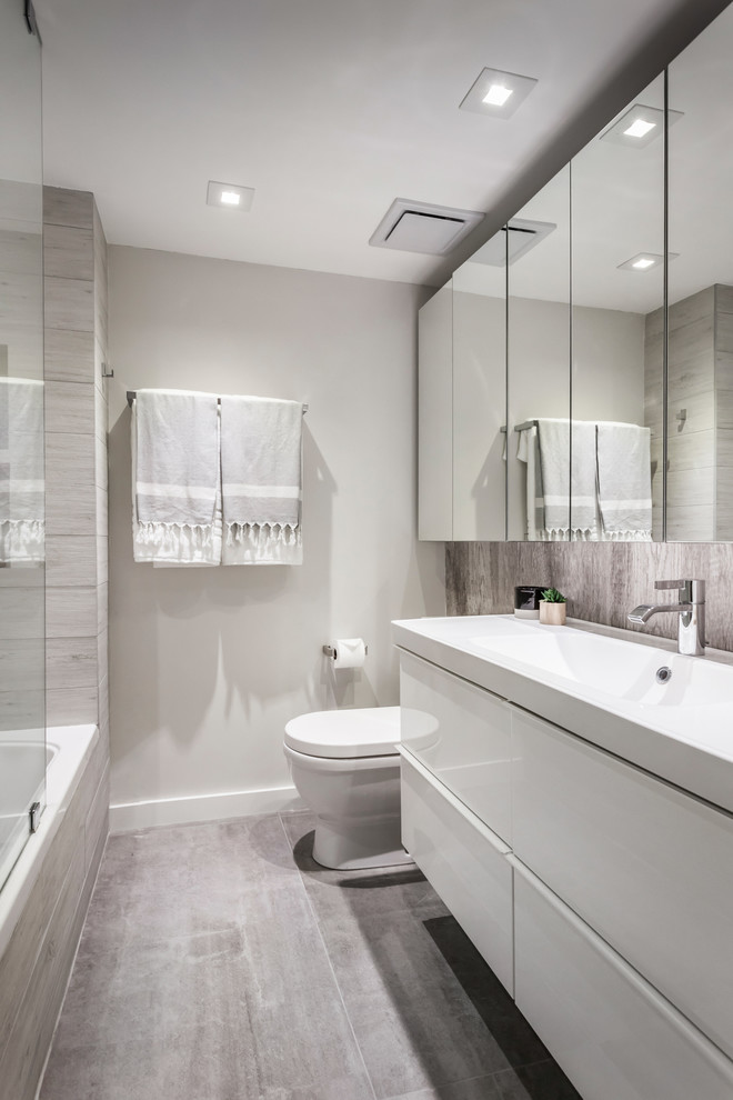 Photo of a small contemporary master bathroom in Miami with flat-panel cabinets, white cabinets, an alcove shower, a two-piece toilet, gray tile, porcelain tile, grey walls, porcelain floors, an integrated sink, grey floor and an open shower.