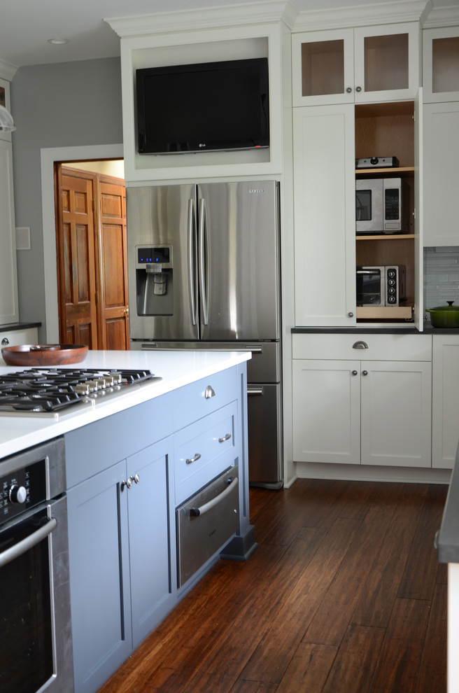 Eat-in kitchen - mid-sized transitional l-shaped dark wood floor eat-in kitchen idea with a single-bowl sink, shaker cabinets, white cabinets, solid surface countertops, white backsplash, glass tile backsplash, stainless steel appliances and an island