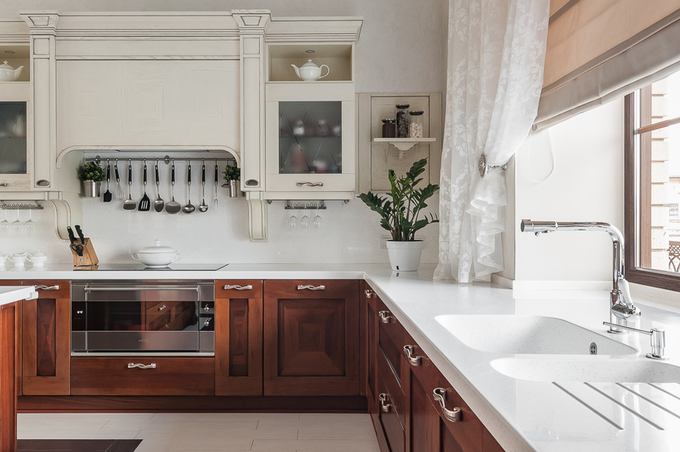 Design ideas for a large traditional l-shaped kitchen in Other with dark wood cabinets, solid surface benchtops, white splashback, stainless steel appliances, porcelain floors, with island, white benchtop, a double-bowl sink, recessed-panel cabinets and window splashback.