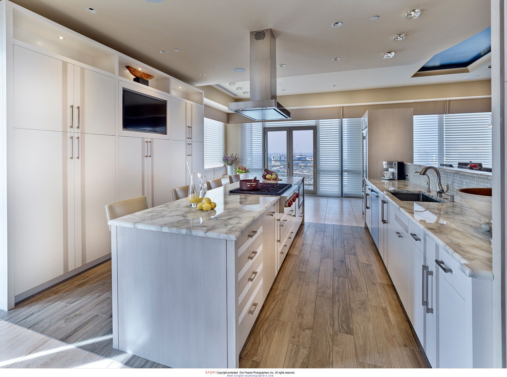 Mid-sized transitional u-shaped eat-in kitchen in Philadelphia with an undermount sink, flat-panel cabinets, white cabinets, marble benchtops, grey splashback, marble splashback, stainless steel appliances, medium hardwood floors, with island, brown floor and white benchtop.