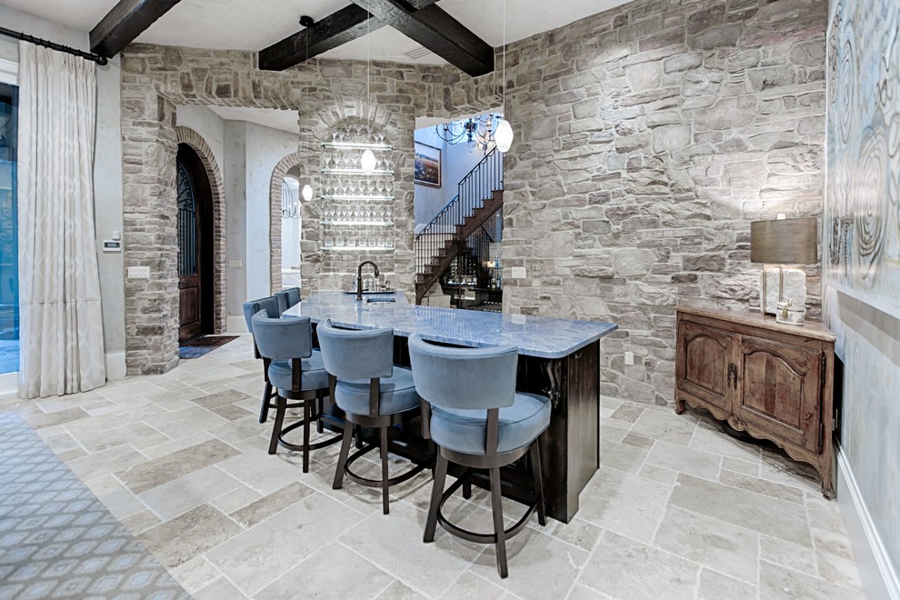 This is an example of a mid-sized mediterranean l-shaped seated home bar in Miami with an undermount sink, raised-panel cabinets, dark wood cabinets, granite benchtops, beige splashback, stone tile splashback, porcelain floors, beige floor and blue benchtop.