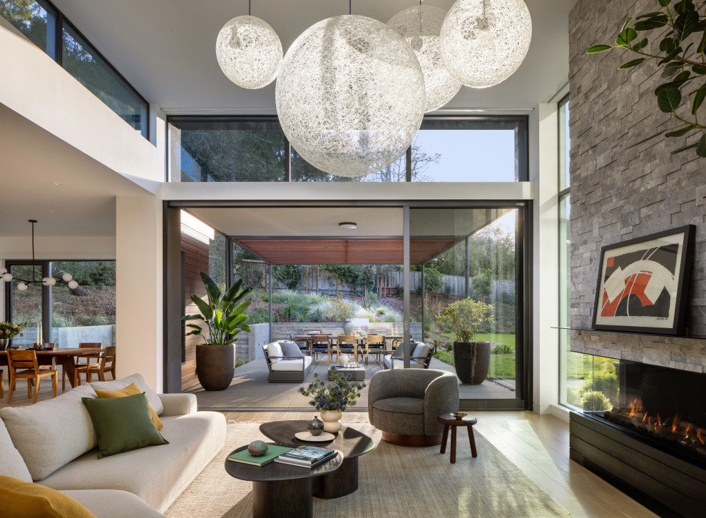 Living room - large contemporary open concept medium tone wood floor living room idea in San Francisco with a standard fireplace, a stacked stone fireplace and no tv