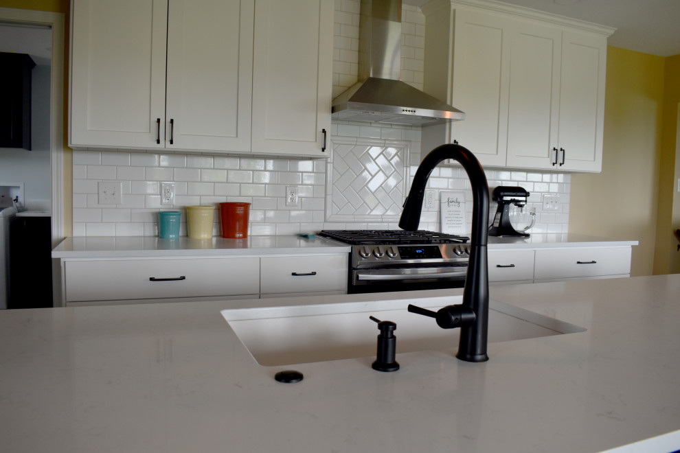 Example of a large minimalist l-shaped vinyl floor and brown floor open concept kitchen design with a drop-in sink, yellow cabinets, quartzite countertops, yellow backsplash, subway tile backsplash, stainless steel appliances, an island and white countertops