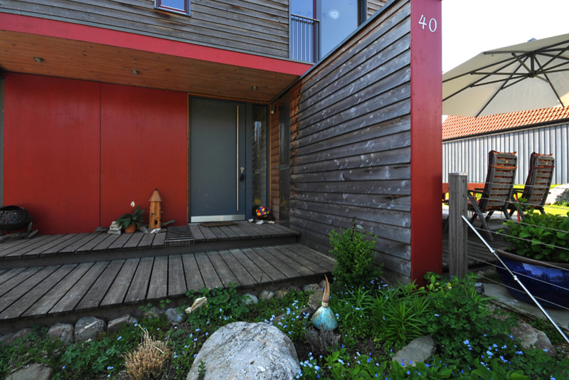 Photo of a mid-sized contemporary front door in Munich with red walls, dark hardwood floors, a single front door and a gray front door.