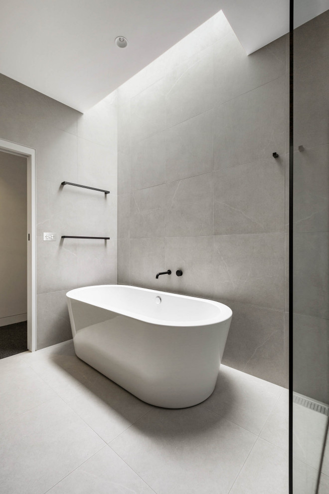 Mid-sized contemporary master bathroom in Melbourne with a freestanding tub, stone tile, grey walls, porcelain floors and grey floor.