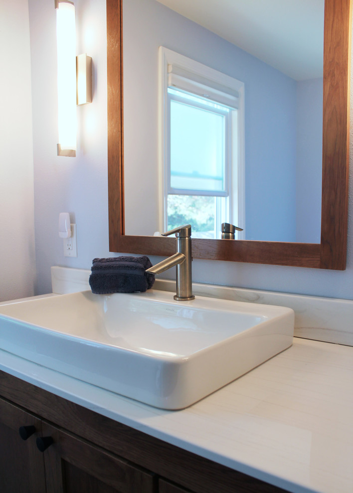 Small modern bathroom in Other with shaker cabinets, medium wood cabinets, an alcove shower, a two-piece toilet, white tile, subway tile, blue walls, ceramic floors, a vessel sink, solid surface benchtops, grey floor, a sliding shower screen and white benchtops.