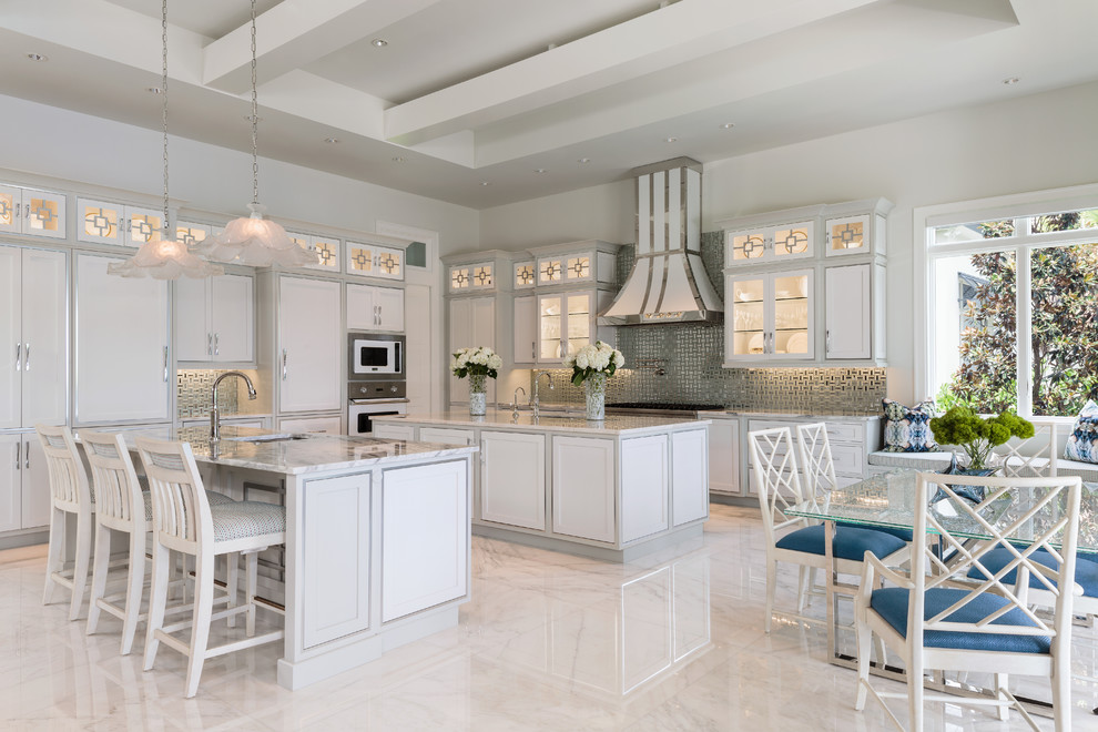Inspiration for a large beach style l-shaped eat-in kitchen in Other with an undermount sink, glass-front cabinets, white cabinets, granite benchtops, metallic splashback, mirror splashback, white appliances, marble floors, multiple islands and multi-coloured floor.