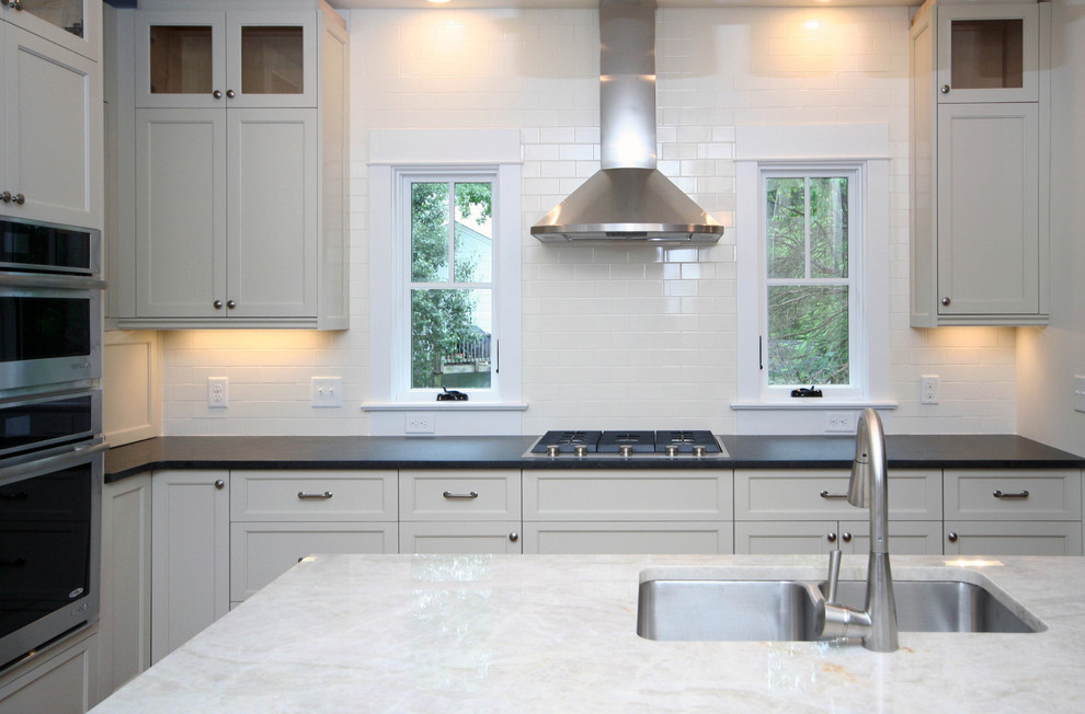 Kitchen - transitional medium tone wood floor kitchen idea in Raleigh with an undermount sink, shaker cabinets, gray cabinets, granite countertops, white backsplash, subway tile backsplash, stainless steel appliances and an island