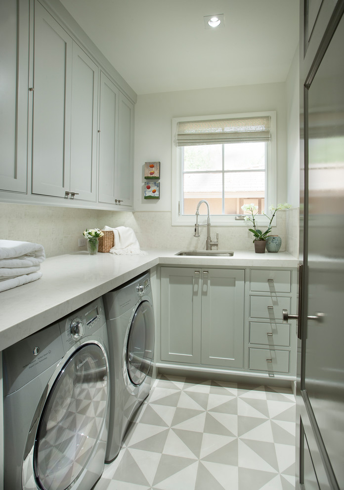 Inspiration for a transitional l-shaped dedicated laundry room in Phoenix with a single-bowl sink, shaker cabinets, grey cabinets, white walls, a side-by-side washer and dryer, multi-coloured floor and white benchtop.