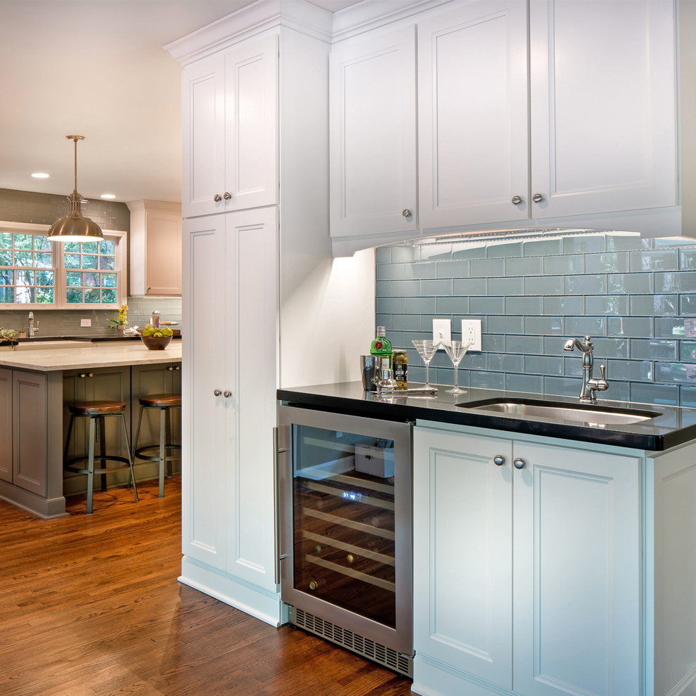 Kitchen - transitional l-shaped dark wood floor kitchen idea with a double-bowl sink, shaker cabinets, white cabinets, marble countertops, blue backsplash, glass tile backsplash, stainless steel appliances and an island
