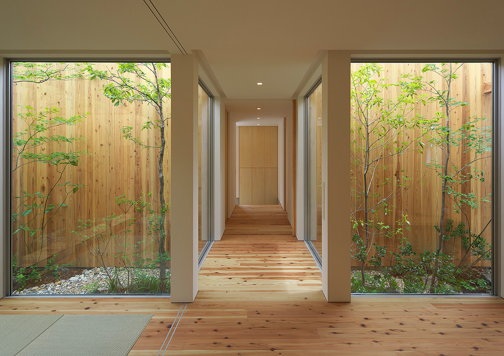 Inspiration for an asian hallway in Osaka with white walls, medium hardwood floors and brown floor.