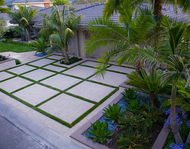 This is an example of a modern front yard driveway in Orange County with a container garden and concrete pavers.