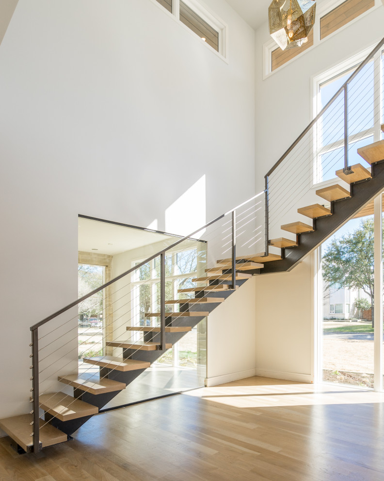 Пример оригинального дизайна: большая лестница на больцах в современном стиле с деревянными ступенями и перилами из смешанных материалов без подступенок