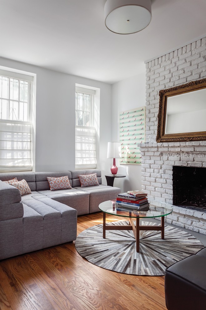 Mid-sized contemporary open concept living room in New York with white walls, medium hardwood floors, a standard fireplace and a brick fireplace surround.