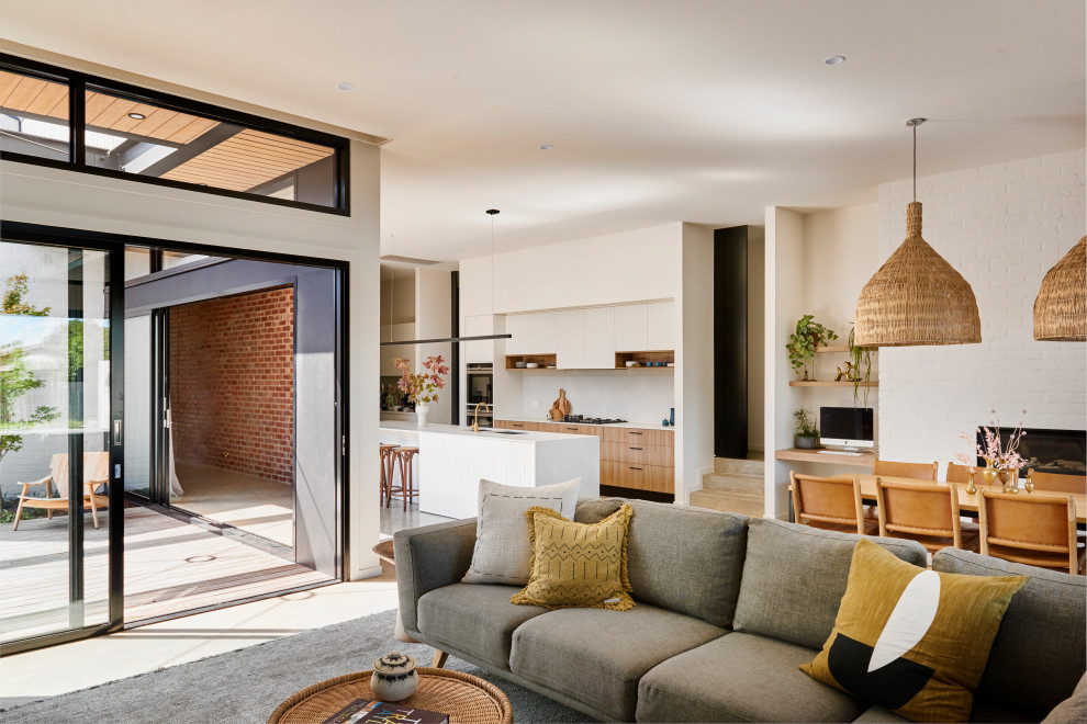 Design ideas for a large contemporary open concept living room in Geelong with white walls, concrete floors, a standard fireplace, a brick fireplace surround, a wall-mounted tv and grey floor.
