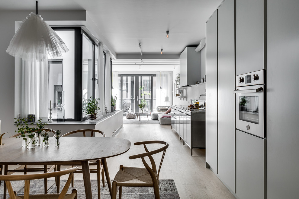 Design ideas for a mid-sized industrial open plan dining in Stockholm with white walls and light hardwood floors.