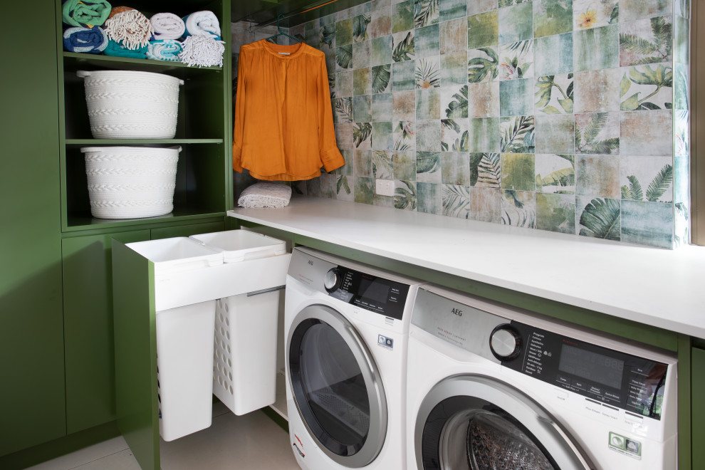 Design ideas for a small modern l-shaped laundry room in Brisbane with a drop-in sink, green cabinets, quartz benchtops, green splashback, porcelain splashback, multi-coloured walls, porcelain floors, a side-by-side washer and dryer, grey floor and white benchtop.