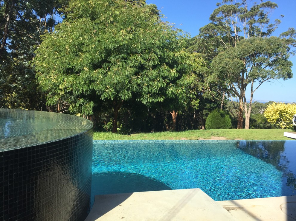 Large contemporary backyard custom-shaped infinity pool in Melbourne with a hot tub and concrete slab.