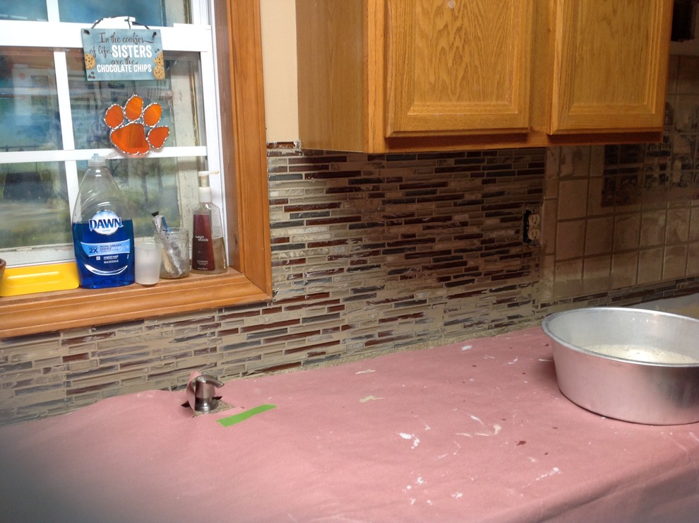 Eat-in kitchen - l-shaped eat-in kitchen idea with an undermount sink, flat-panel cabinets, brown backsplash, glass tile backsplash, stainless steel appliances and a peninsula
