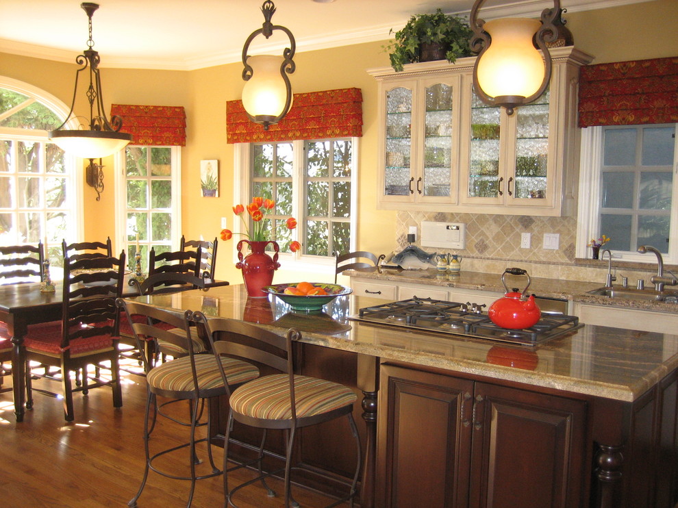 Photo of a traditional eat-in kitchen in Los Angeles with glass-front cabinets, beige cabinets and beige splashback.