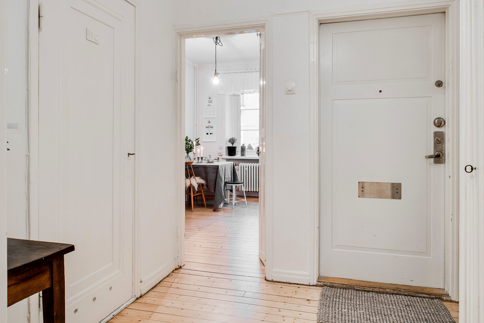 This is an example of a scandinavian hallway in Gothenburg with white walls and light hardwood floors.