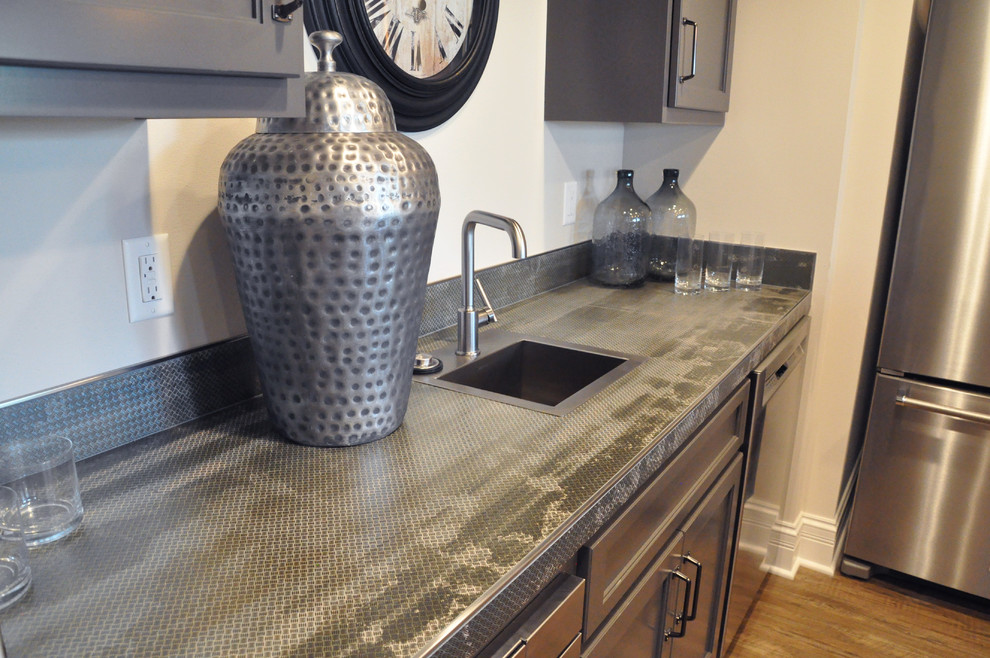 This is an example of a large transitional galley wet bar in Milwaukee with raised-panel cabinets, grey cabinets, tile benchtops and vinyl floors.