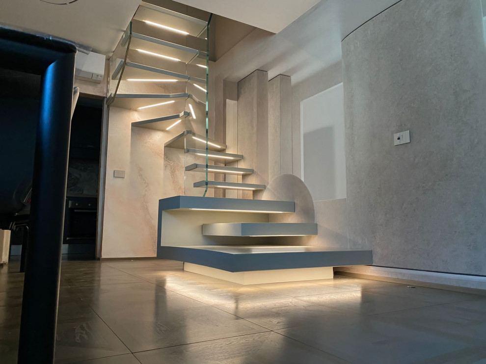 This is an example of a medium sized contemporary wood u-shaped glass railing staircase in Milan with open risers and wallpapered walls.