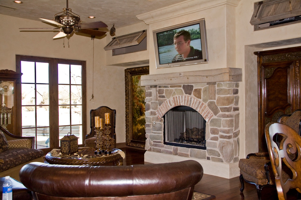 Photo of a country family room in Austin with dark hardwood floors, a standard fireplace and a stone fireplace surround.