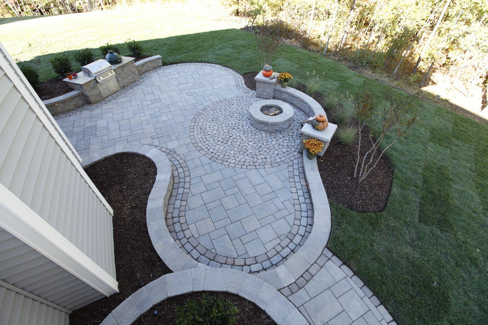 This is an example of a large traditional backyard patio in Richmond with a fire feature, concrete pavers and no cover.
