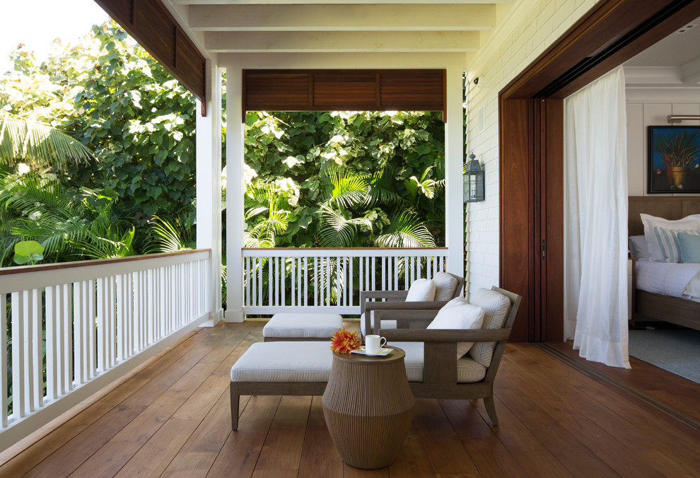 Inspiration for a large tropical balcony in Hawaii with a roof extension and wood railing.