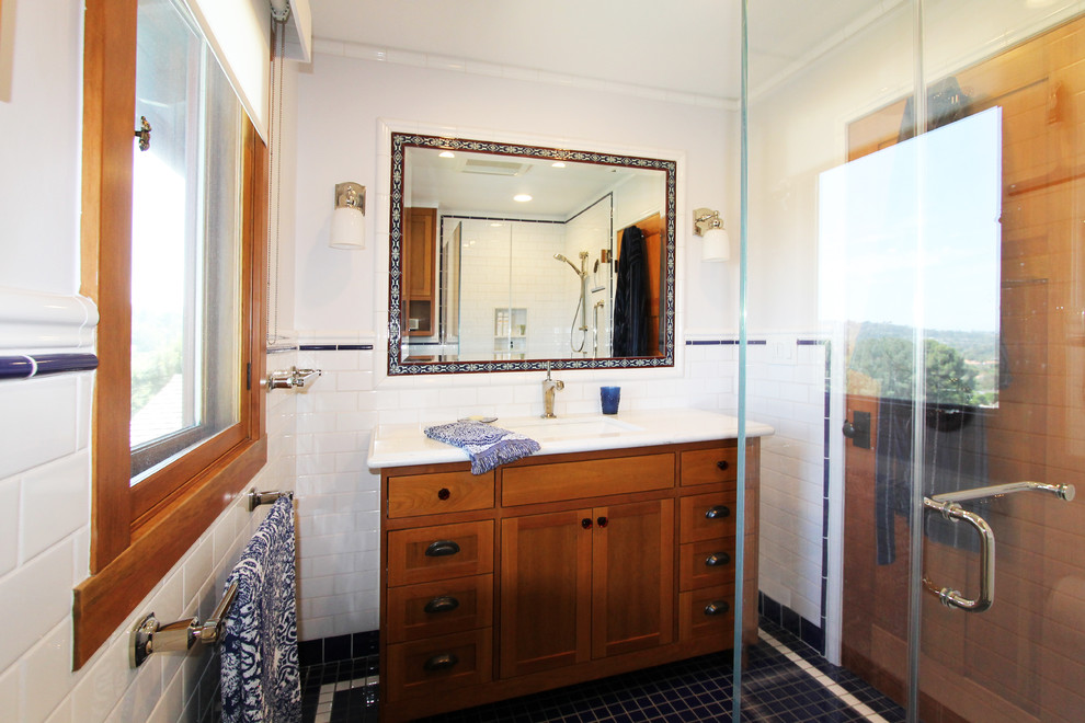 Mid-sized arts and crafts bathroom in Los Angeles with beaded inset cabinets, medium wood cabinets, a curbless shower, white tile, subway tile, white walls, mosaic tile floors, an integrated sink, black floor, a hinged shower door, white benchtops, a single vanity and a built-in vanity.