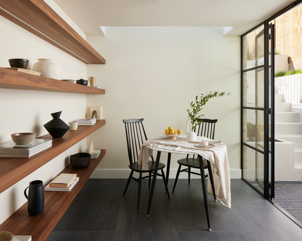 Diseño de comedor actual pequeño sin chimenea con con oficina, paredes blancas, suelo de baldosas de porcelana, suelo negro y bandeja
