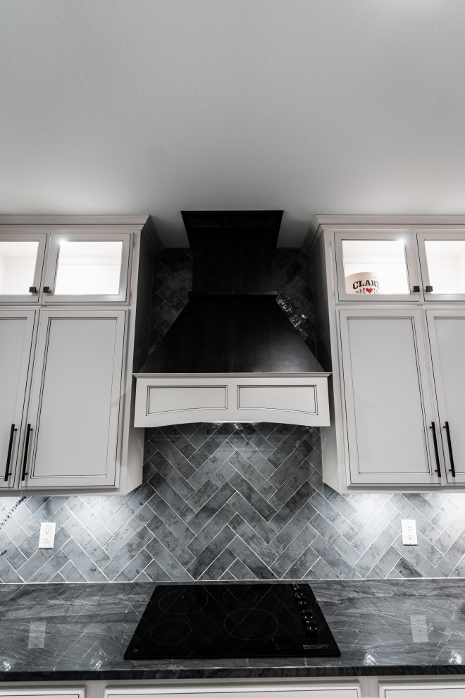 Open concept kitchen - huge transitional l-shaped laminate floor, gray floor and tray ceiling open concept kitchen idea with an undermount sink, flat-panel cabinets, white cabinets, quartz countertops, gray backsplash, ceramic backsplash, black appliances and an island