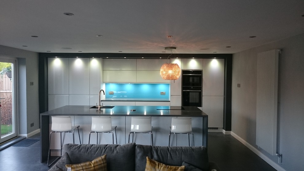 Photo of a large contemporary single-wall eat-in kitchen in Other with an undermount sink, flat-panel cabinets, white cabinets, quartzite benchtops, blue splashback, black appliances, vinyl floors and with island.
