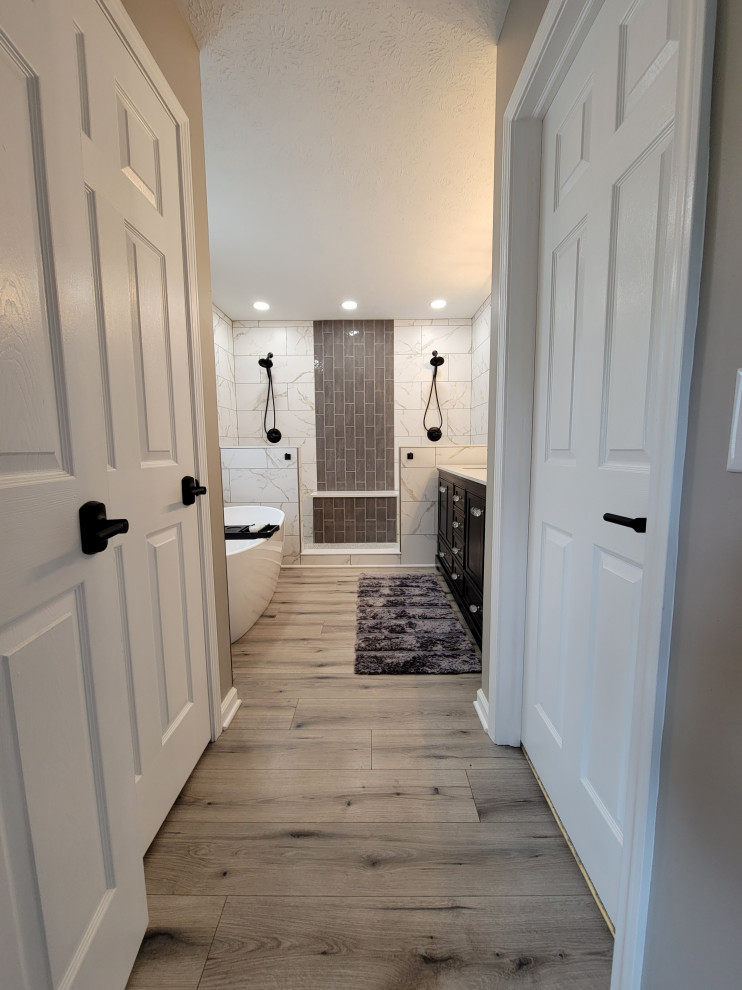 Medium sized traditional bathroom in Indianapolis with black cabinets, a freestanding bath, a double shower, black and white tiles, ceramic tiles, beige walls, laminate floors, an integrated sink, engineered stone worktops, beige floors, an open shower, white worktops, double sinks and a freestanding vanity unit.