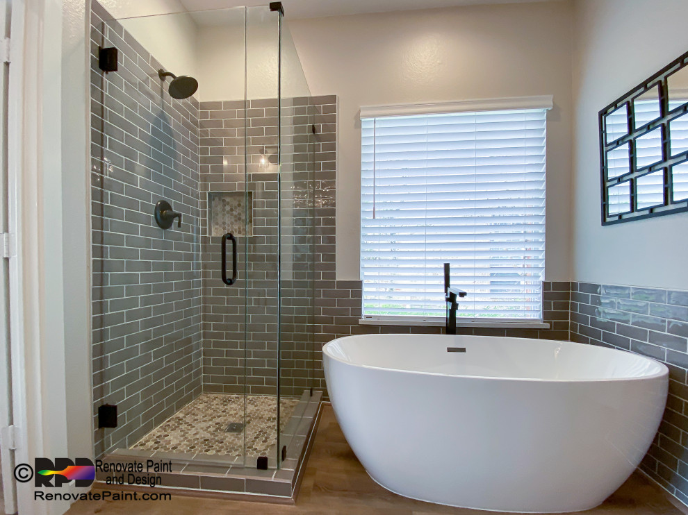 This is an example of a large contemporary master bathroom in Austin with shaker cabinets, white cabinets, a freestanding tub, an alcove shower, a one-piece toilet, gray tile, ceramic tile, beige walls, ceramic floors, an undermount sink, engineered quartz benchtops, beige floor, a hinged shower door, white benchtops, a niche, a double vanity and a freestanding vanity.