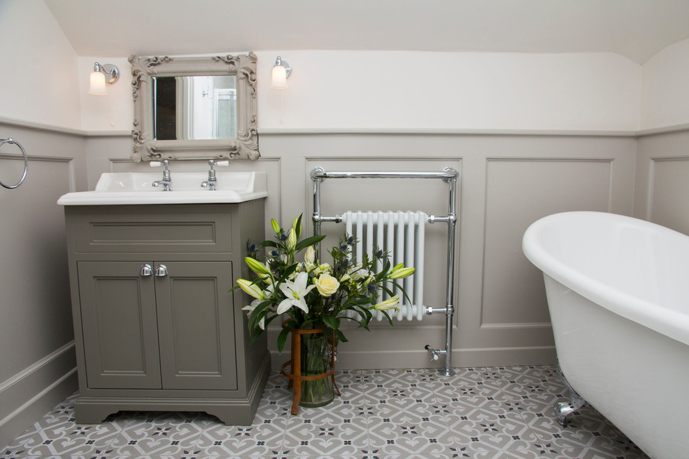 Photo of a Medium Sized classic bathroom With Freestanding Cabinets, Grey Cabinets, a Freestanding Bath, a Shower/Bath Combination, a Two-piece Toilet, Grey Tiles, Ceramic Tiles, Grey Walls, Cement Flooring and an Integrated Sink.